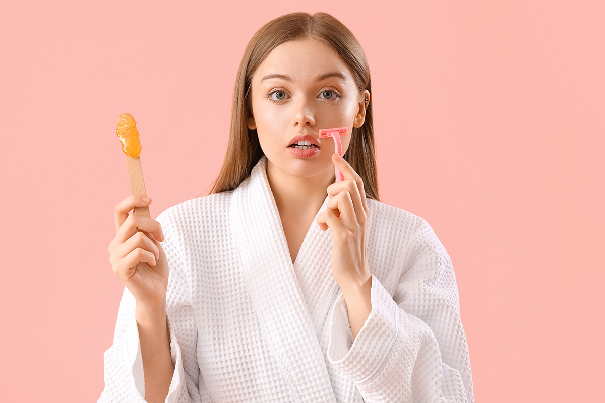 Young woman holding spatula with sugaring paste and razor