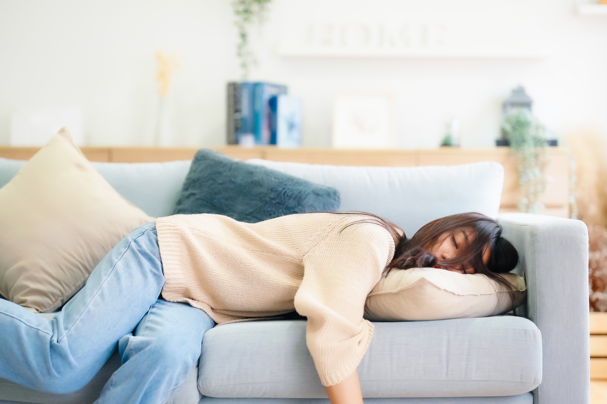 Woman resting at home on couch, feeling exhausted after work, lacking energy, or overworked, too tired, and lacking motivation