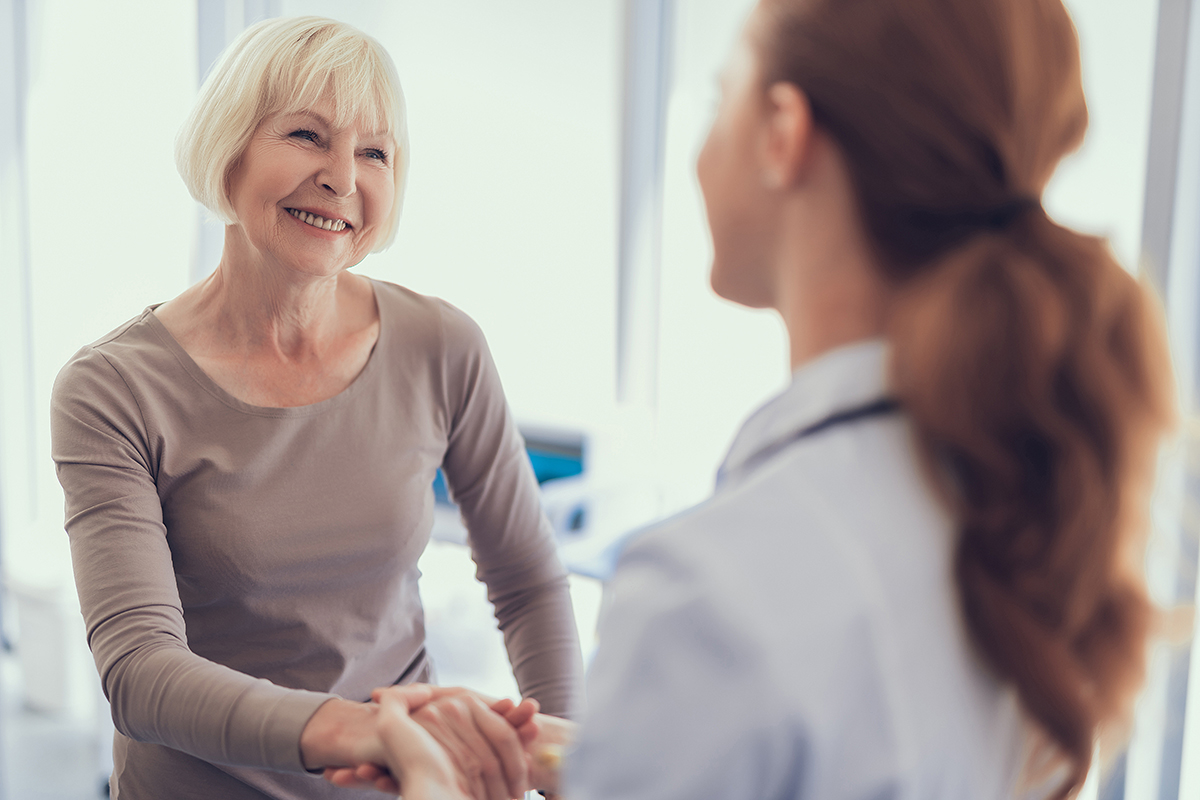 Focus on smiling lady shaking hands with physician after visit to clinic