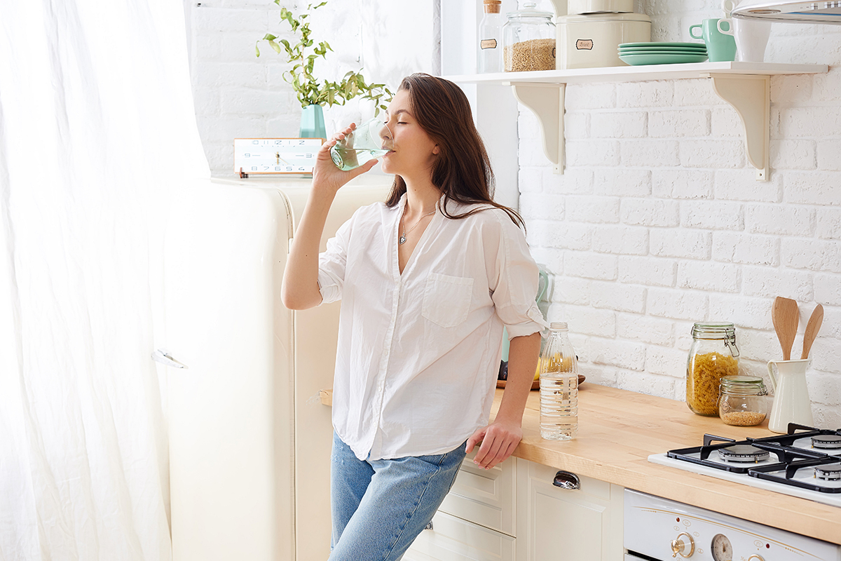 Gorgeous woman drinking water in her kitchen