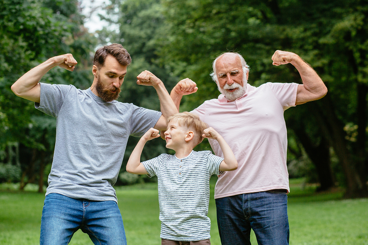Grandpa, father and his son smiling and showing their muscles outdoor