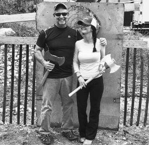 Grayscale photo of a couple holding toy axes outdoor